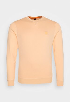 Licht perzikkleurige sweatshirt met lange mouwen en een ronde hals, geribbelde boorden en zoom, en een klein vierkant logo op de linkerborst.