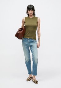 Haut sans manches vert olive, jean bleu clair déchiré, sac à main en cuir marron et ballerines imprimé léopard. Design minimaliste, coupe décontractée.