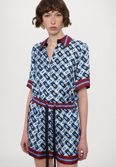 Rochie cămașă scurtă cu mâneci scurte, cu un model albastru, guler și talie roșie. Are un design geometric cu accente negre și un șnur de strângere.