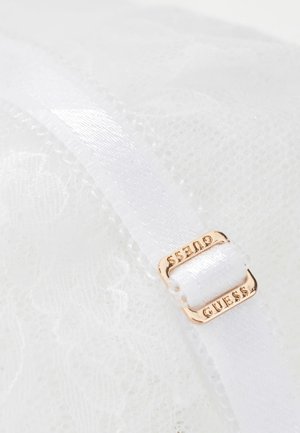 Biała tkanina koronkowa z białym satynowym regulowanym paskiem z małą złotą klamrą z wygrawerowanym napisem "GUESS."