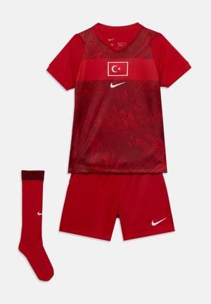 Červený fotbalový dres s vzorovaným trikem obsahujícím tureckou vlajku, červené šortky a odpovídající červené ponožky s bílými logy Nike.