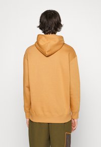 Felpa con cappuccio di un giallo dorato, caratterizzata da una vestibilità comoda, polsini e orlo a costine. Il tessuto ha una superficie liscia, con dettagli di cucitura ridotti al minimo.