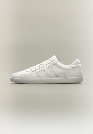 Valge madala säärega tossu paeltega, tekstuurse tald ja Tommy Hilfigeri logoga küljel, näidatud profiilist lihtsal taustal.