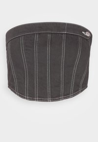 Svart tygkeps med texturerad yta, vertikal vit söm och en böjd skärm. Har en metallknapp som accent vid sidan.