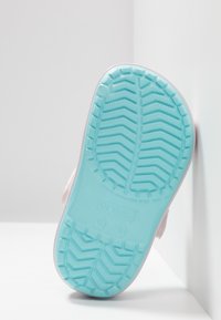 Roze rubberen zool met een gestructureerd lichtblauw patroon met zigzaglijnen en cirkelvormige accenten, onder een hoek tegen een neutrale achtergrond.