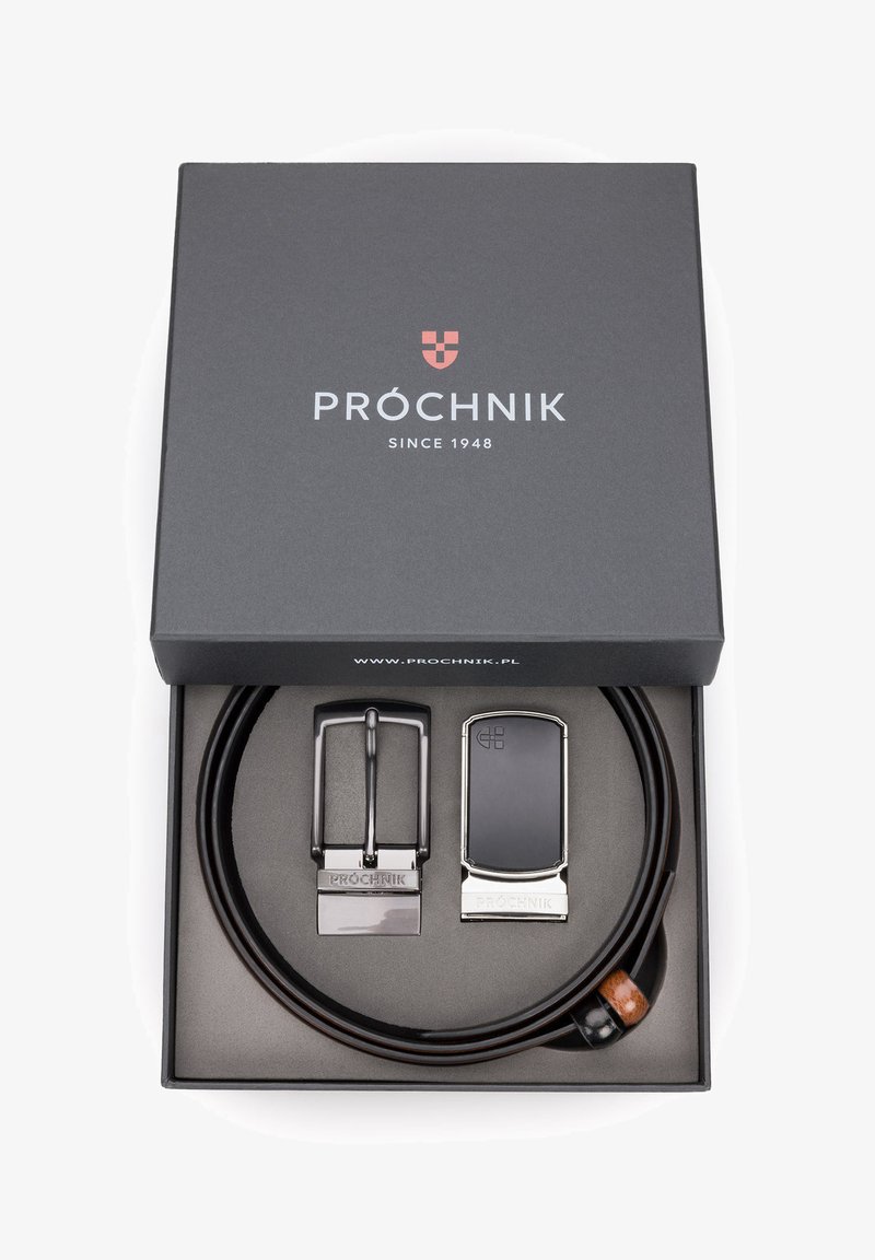 Brązowy skórzany pasek z dwiema metalowymi klamrami, jedną srebrną i jedną czarną. Zapakowany w czarne pudełko z białym brandingiem i czerwonym logo.