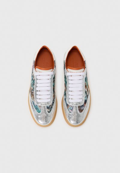 Silver metallic sneakers with a textured surface, white laces, and a brown insole. Features colorful pattern accents along the sides.