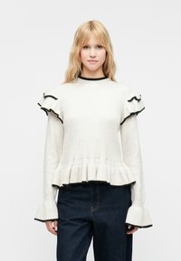 Bela rebrasta majica z črnimi obrobami, z nabrano zaveso in razširjenim spodnjim robom. Mehka tekstura in prilegajoč dizajn.