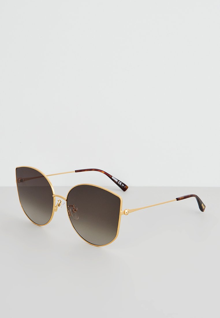 Sonnenbrille mit übergroßen, verlaufenden Gläsern, goldenem Metallrahmen und einem Gestell aus braunem Schildpatt. Winkliges Design mit klaren Nasenpads.