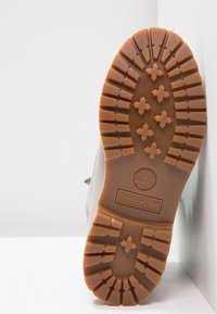 Brown rubber outsole with a textured pattern of stars and grooves; features the Timberland logo. Designed for traction and durability.