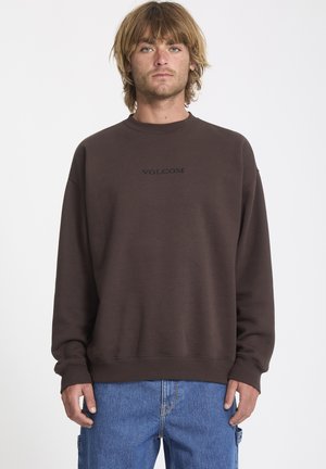 Brązowa bluza z okrągłym dekoltem, z kontrastowym czarnym logo "VOLCOM" wyszytym na klatce piersiowej. Miękka tkanina, luźny krój i ściągacze przy mankietach.