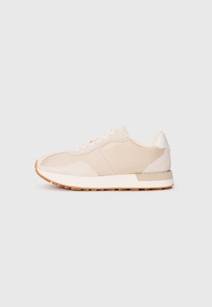 Sneaker color beige chiaro con tomaia in mesh e suede, dettagli bianchi, chiusura con lacci e suola in gomma. Presenta un design sportivo classico.