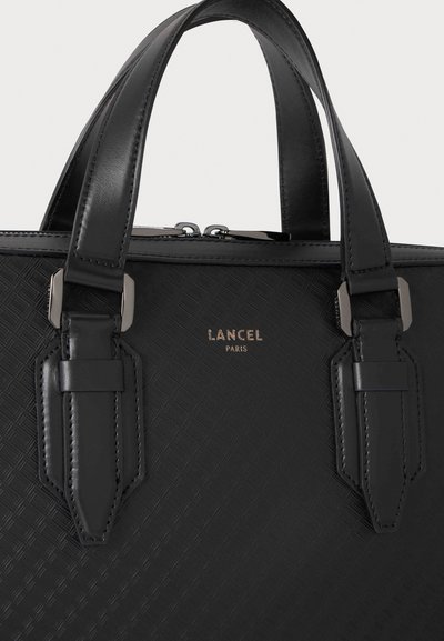 Близък план на черна текстурирана чанта Lancel Paris с две дръжки, метални елементи със сребристо покритие и горен цип.
