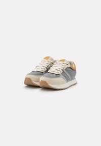 Sport shoes with a gray fabric upper, beige suede accents, flat cream laces, and a light brown rubber sole. Textured design, cushioned fit.
