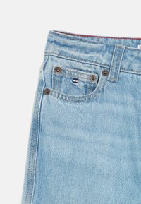 Lyseblå denimjeans med en tapered design. Har fem lommer, brune metallknapper og en liten logoetikett på frontlommen.