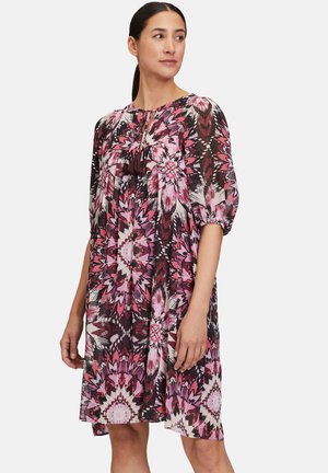 Short-sleeve, knee-length dress in pink, black, and white floral pattern with a keyhole neckline and tassel detail. Light, textured fabric.