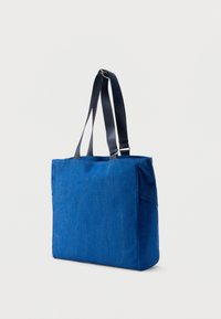 Μπλε τσάντα tote από ύφασμα με σκούρες λαβές, ορθογώνιο σχήμα και φερμουάρ στο πάνω μέρος. Διαθέτει ραμμένες ραφές και πλαϊνή τσέπη.