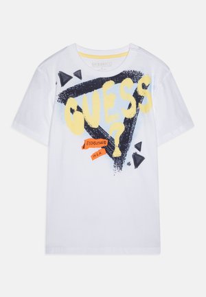 Camiseta blanca de algodón con un diseño gráfico que incluye la palabra "GUESS?" en amarillo, triángulos negros y una etiqueta naranja que dice "ESTABLECIDO EN L.A."