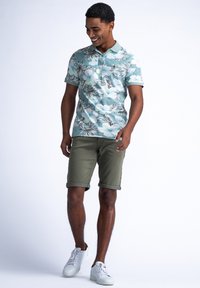 Minttuvihreä kukkakuosisia lyhythihainen polo-paita, jota on matchattu oliivinvihreisiin lyhennettäviin shortseihin. Asusteena valkoiset tennarit.