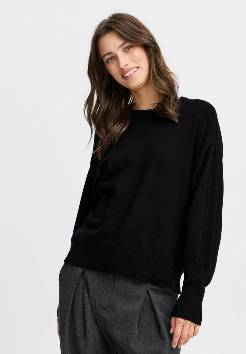 Schwarzer gestrickter Pullover mit Rundhalsausschnitt, gerippten Bündchen und Saum. Verfügt über eine lockere Passform mit vertikaler Rippenstruktur an den Ärmeln und weichem Material.