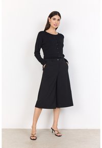 Black long-sleeve cardigan with button closure layered over matching wide-leg culottes. Features a fitted waist and side pockets.