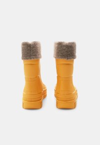 Botas de goma amarillas con un puño gris de felpa, que presentan una superficie texturizada y un diseño de suela resistente para mayor tracción.