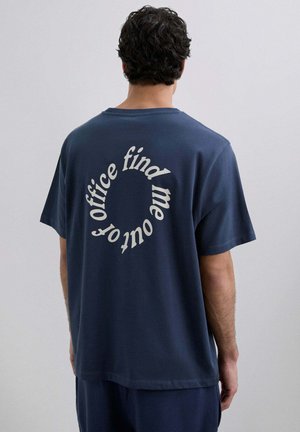 Camiseta de algodón de color azul marino con mangas cortas, que presenta un texto curvado en blanco en la parte de atrás que dice "encuéntrame fuera de la oficina".