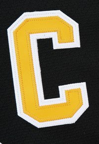 Gelb und weiß gestickter Buchstabe "C" Patch auf schwarzem Stoffhintergrund.