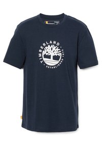 Námorně modré tričko s krátkým rukávem vyrobené z bavlny, které má bílé kruhové logo s grafikou stromu a nápisem "TIMBERLAND ESTABLISHED 1973".