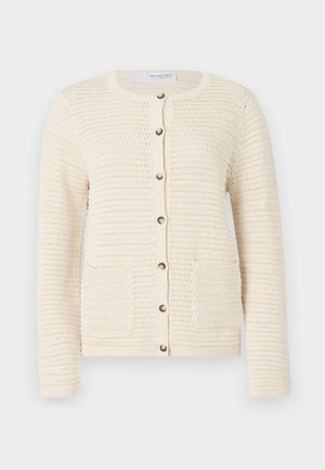 Neulecardigan vaaleassa valkoisessa, jossa on pyöreä kaula-aukko, nappikiinnitys, kaksi etutaskua ja teksturoitu kuvio koko kankaan läpi.