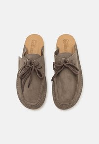 Brown suede slip-on shoes with a rounded toe, featuring decorative brown laces and a natural-colored insole marked "Clarks Originals."