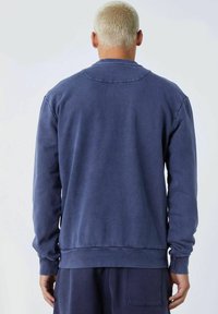 Sudadera de color azul marino hecha de una tela suave, con un escote redondo, mangas largas y un dobladillo acanalado. Diseño simple y limpio sin logotipos.