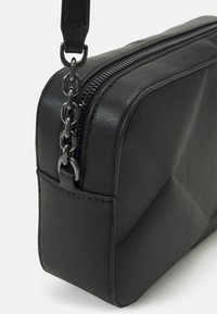 Borsa nera in ecopelle con forma rettangolare, dotata di una zip argentata e un dettaglio in catena sulla tracolla. Texture liscia, design minimalista.
