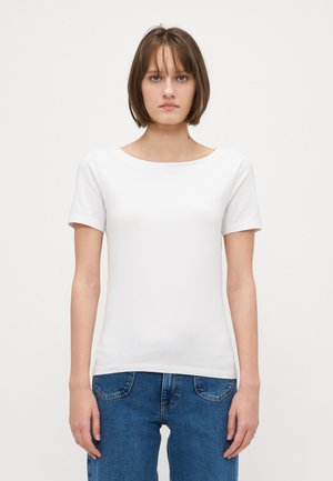 Hvit tettsittende t-skjorte med rund hals og korte ermer, laget av glatt bomullsstoff, sammen med blå jeans. Enkelt design.