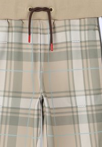 Pantalon à carreaux beige et bleu clair avec cordon de serrage marron avec embouts rouges, taille élastique et subtil logo "HUGO".