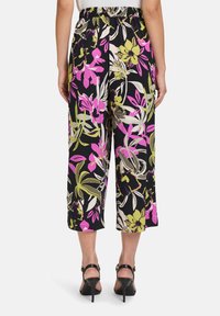 Czarne spodnie 3/4 w kwiatowy wzór, ozdobione różowymi, fioletowymi i zielonymi kwiatami. Elastyczna talia i lekka struktura materiału.