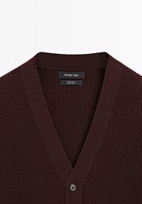 Cardigan in cotone a coste marrone scuro con scollo a V e un singolo bottone nero, etichettato Massimo Dutti, prodotto in Cina.