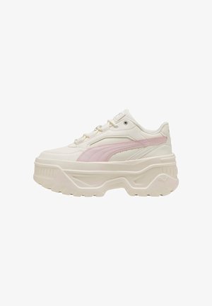 Sneakers bianchi chunky con un accento rosa chiaro, parte superiore texturizzata, suola spessa e branding Puma in evidenza. Presentano un design con lacci e colletto imbottito.