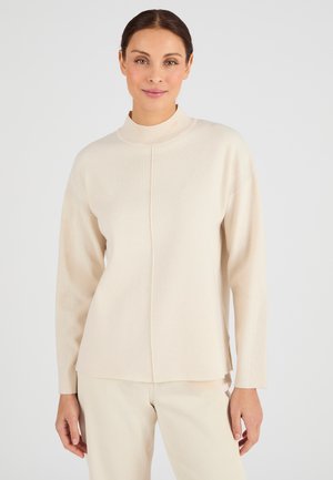 Maglione beige a maniche lunghe con colletto alto, texture a costine e spacchi laterali. Presenta una sottile cucitura centrale per un tocco di dettaglio in più.