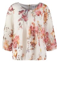 Blouse blanche avec imprimé floral rose, orange et jaune, devant plissé, encolure ronde, manches trois-quarts transparentes et fermeture éclair au col arrière.