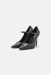 Zwarte lakleren hoge hakken met spitse neuzen, enkelbandjes en zilveren studs langs de randen. Heeft een slanke stilettohak.