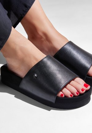 Black leather slide sandals with a wide strap and a textured finish. Features a flat black sole and a small silver accent on the strap.