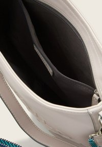 Borsa beige con esterno liscio e forma strutturata. Caratterizzata da una fodera in tessuto scuro, tasca con zip e tracolla regolabile.
