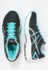 Scarpe da ginnastica nere con tomaia in rete, dettagli turchesi e suola bianca con grip testurizzato. Lacci in turchese coordinato.