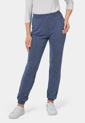Marineblaue Jogginghosen aus weichem Stoff, mit elastischem Bund, seitlichen Taschen und gerafften Bündchen, kombiniert mit weißen Turnschuhen.