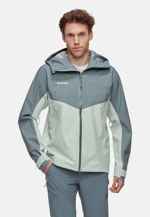Veste légère bicolore en vert menthe pâle et gris ardoise. Elle dispose d'une capuche, de poches zippées et est fabriquée en matériau résistant à l'eau.