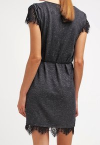 Robe grise en tissu doux, avec des accents en dentelle sur les manches et l'ourlet, dotée d'une taille ceinturée et d'une silhouette décontractée.