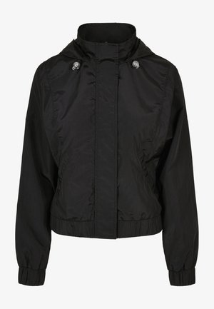 Must mustaga ülikond musta esikrae, elastsete mansettide ja tõmmatud vöökohtadega. Omab nööpkinnitusi ja sujuvat, kergetstoffi.