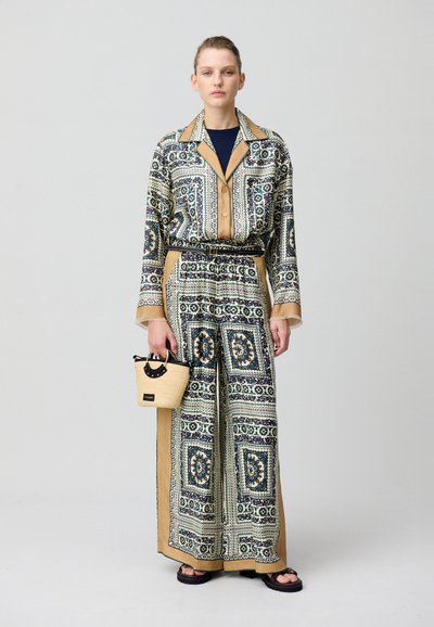 Conjunto de dos piezas con estampado en azul, verde y beige, compuesto por una blusa de botón, pantalones de pierna ancha, un cinturón negro y un pequeño bolso de mimbre.