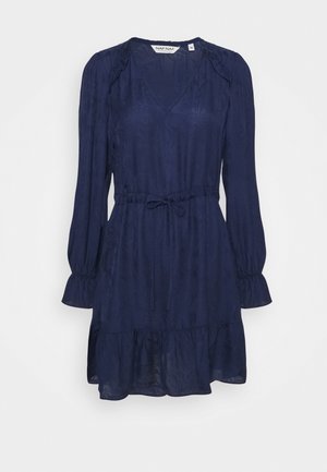 Navyblaues Kleid mit langen Puffärmeln, tailliertem Saum und gestuften Rüschen am unteren Ende. Hergestellt aus leichtem, strukturiertem Stoff.